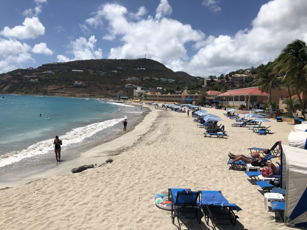 Expanse of beach with sunbathers on loungers.