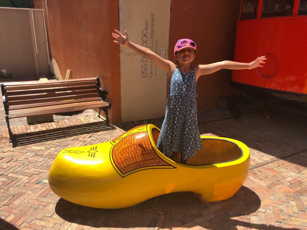 Girl posing in lifesize Dutch shoe in St. Maarten.