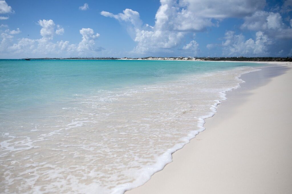 Jewel colored water lapping white surf onto a white sand beach.