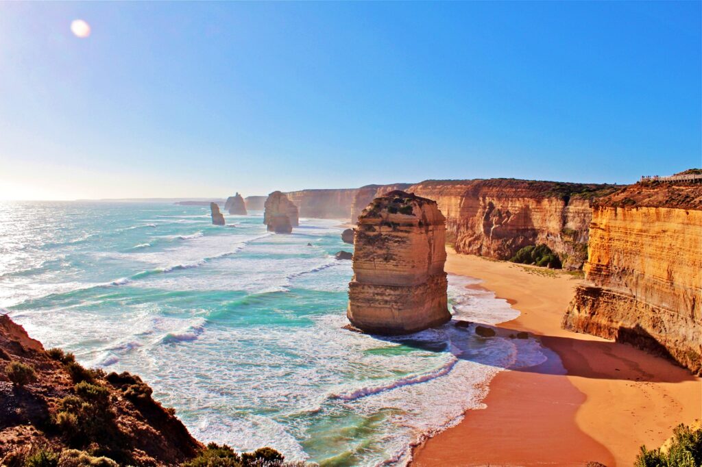 Ocean waves lapping onto golden sand below the Great Ocean Road, a travel bucket list must in Australia.