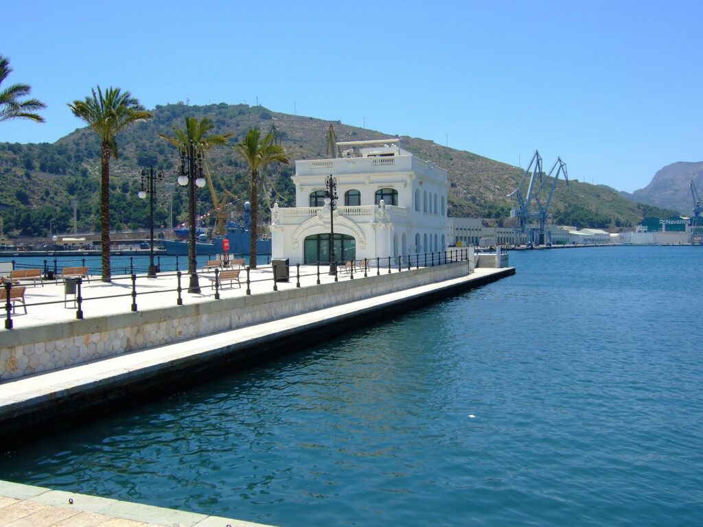 A pier with a white building at the end over a body of water.