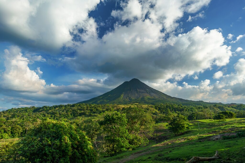 Green landscape leading up to a green volcano in the distance in Costa Rica.