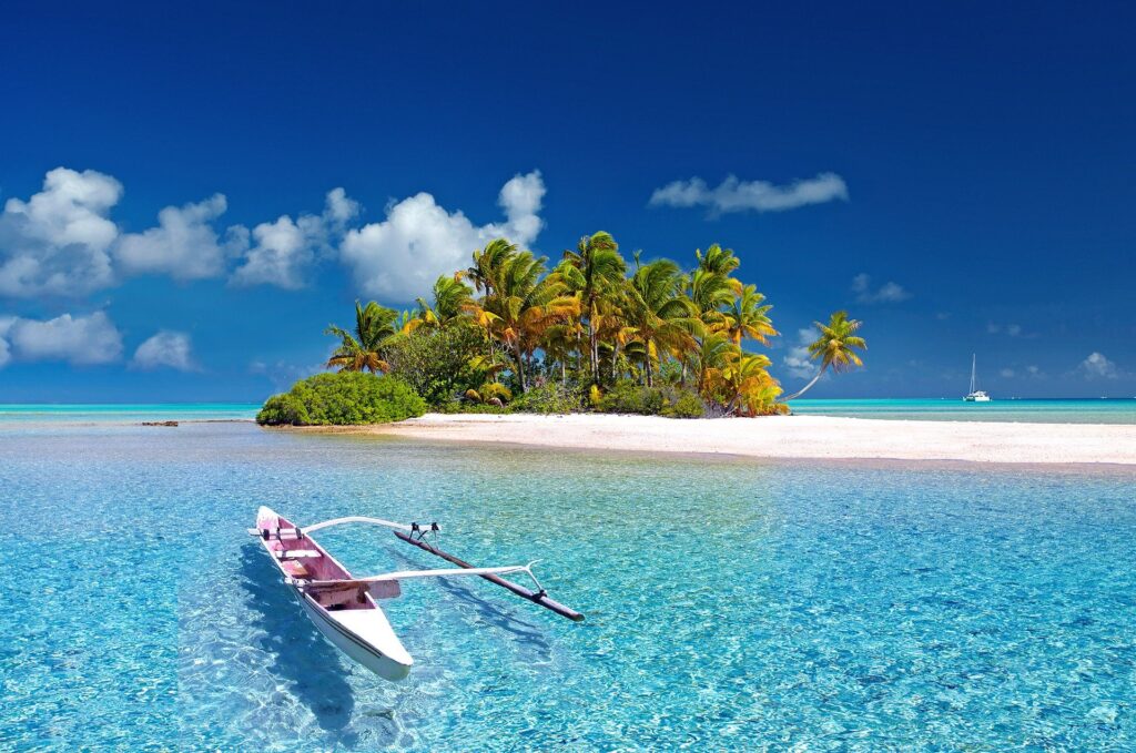 A solo outrigger type boat floating in sparkling water in French Polynesia.