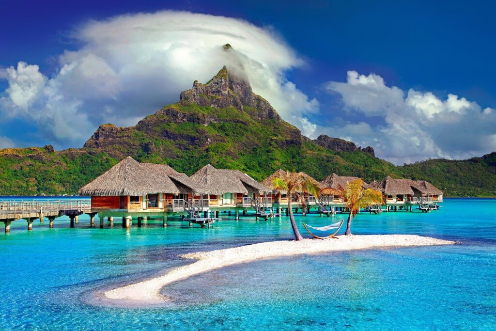 Overwater bungalows before a green mountain in the travel bucket list must French Polynesia.