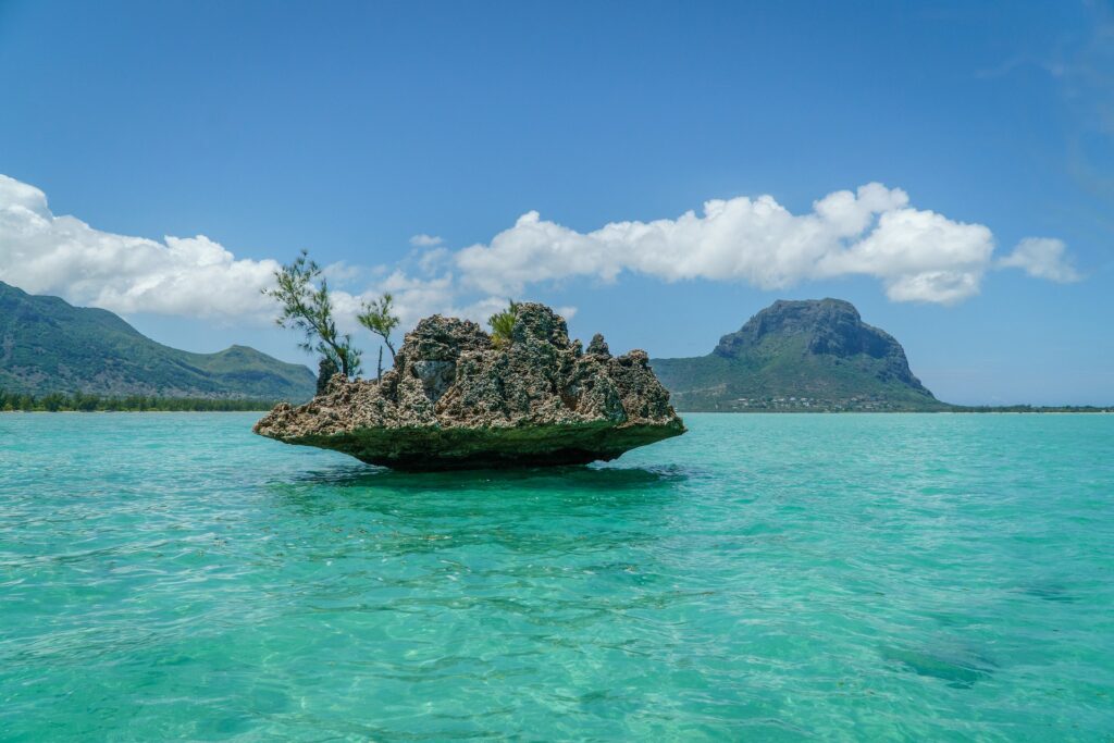 A craggy rock sitting solo within an aqua lagoon.