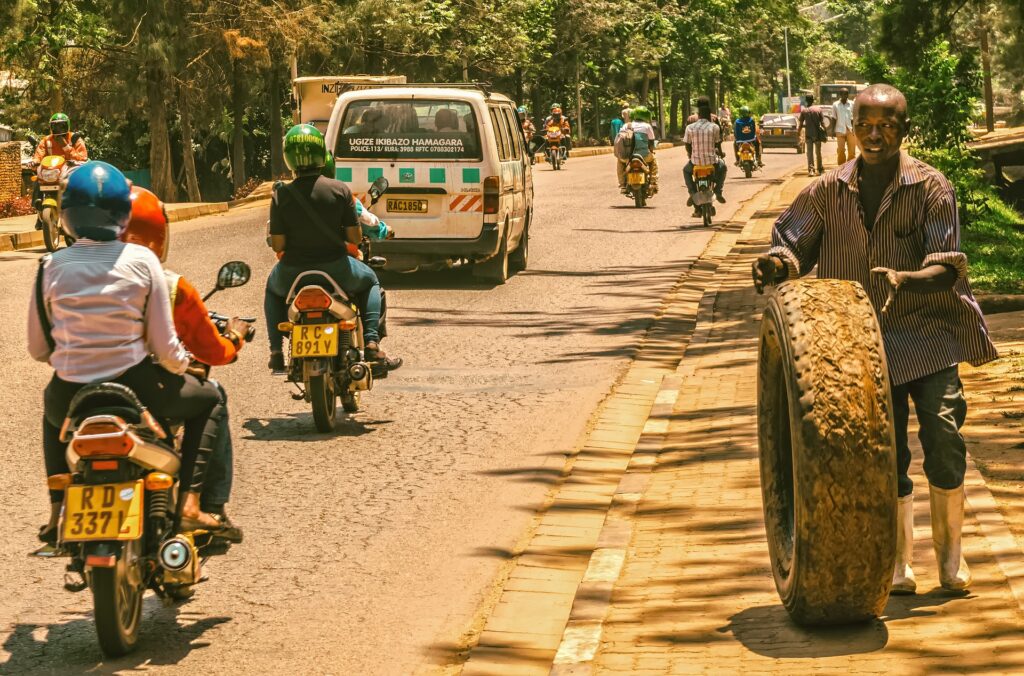 Motorcycles, mini bus and man rolling tired down busy roadside in Africa.