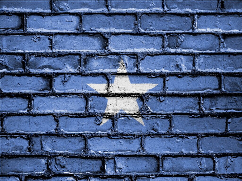 The blue background and white star of the Somalian flag painted on a brick wall.