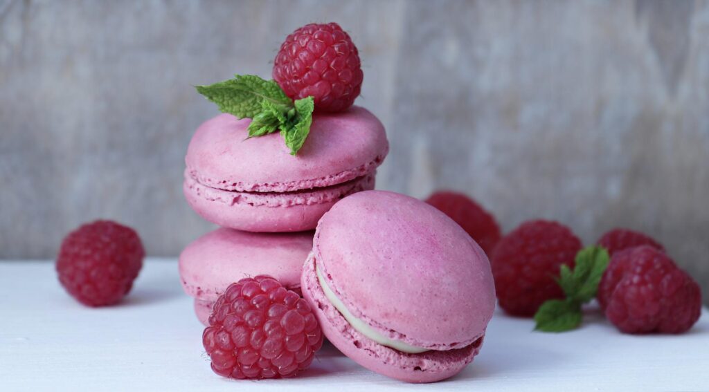 A stack of pink macarons and raspberries.