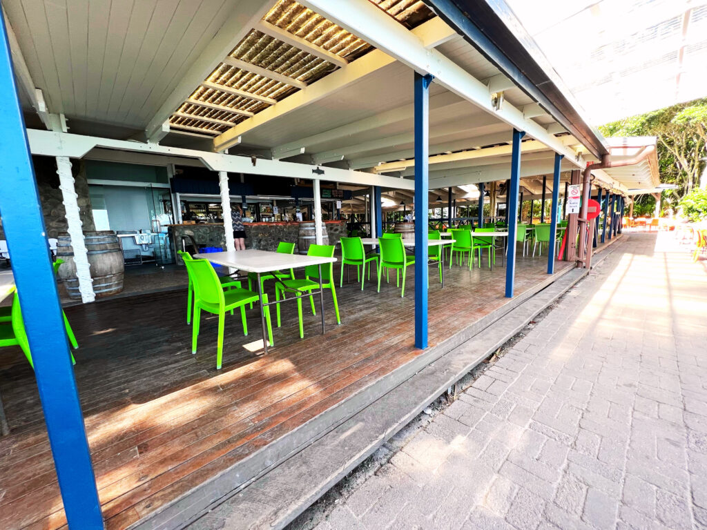 Covered outdoor patio with lime green chairs and white tables.