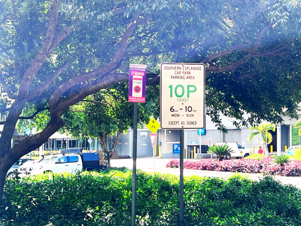 Informational signs next to a bush and below a tree.