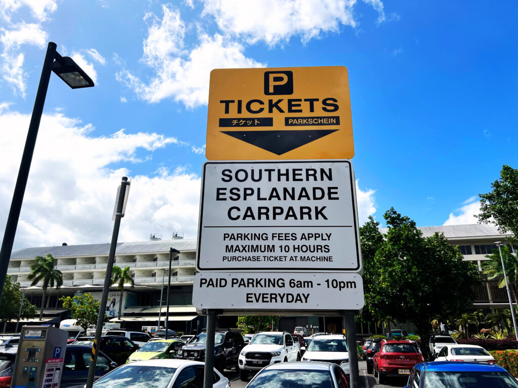 Orange and white informational sign in parking lot.