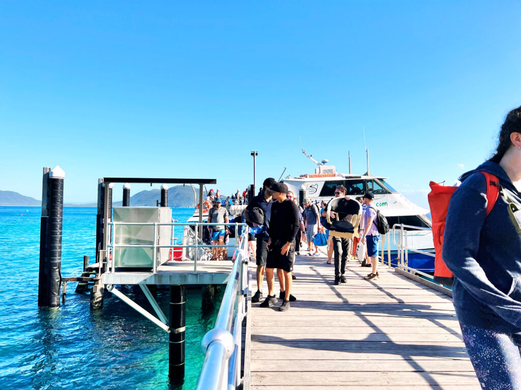 A boat dock with people mingling and a ferry docked next to it.