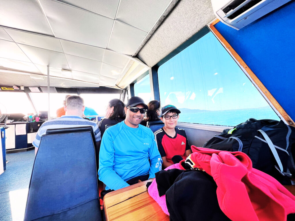 Passengers sitting inside on blue seats in an older ferry.