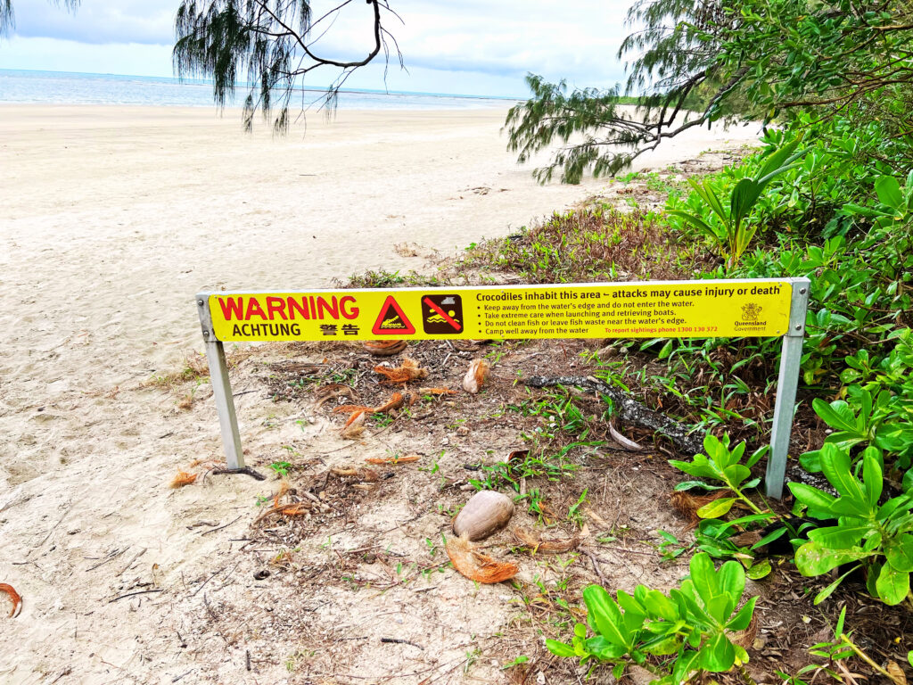 Warning sign posted in sand on beach.