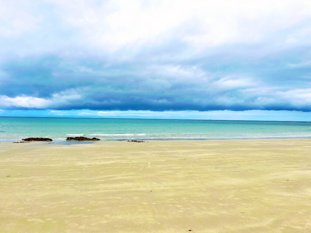 Beach in foreground with aqua sea in background.