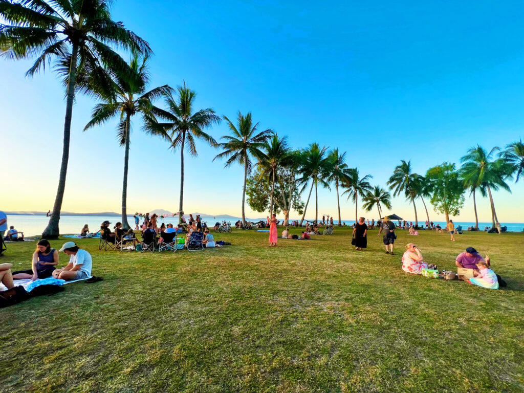 Palm trees on a lawn with people having picnics and watching the sunset in Rex Smeal Park.