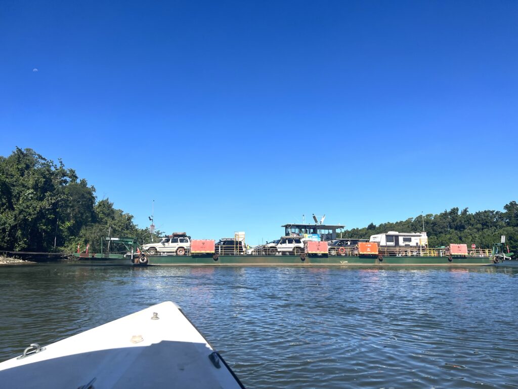 A ferry loaded with transiting vehicles floating across a river.