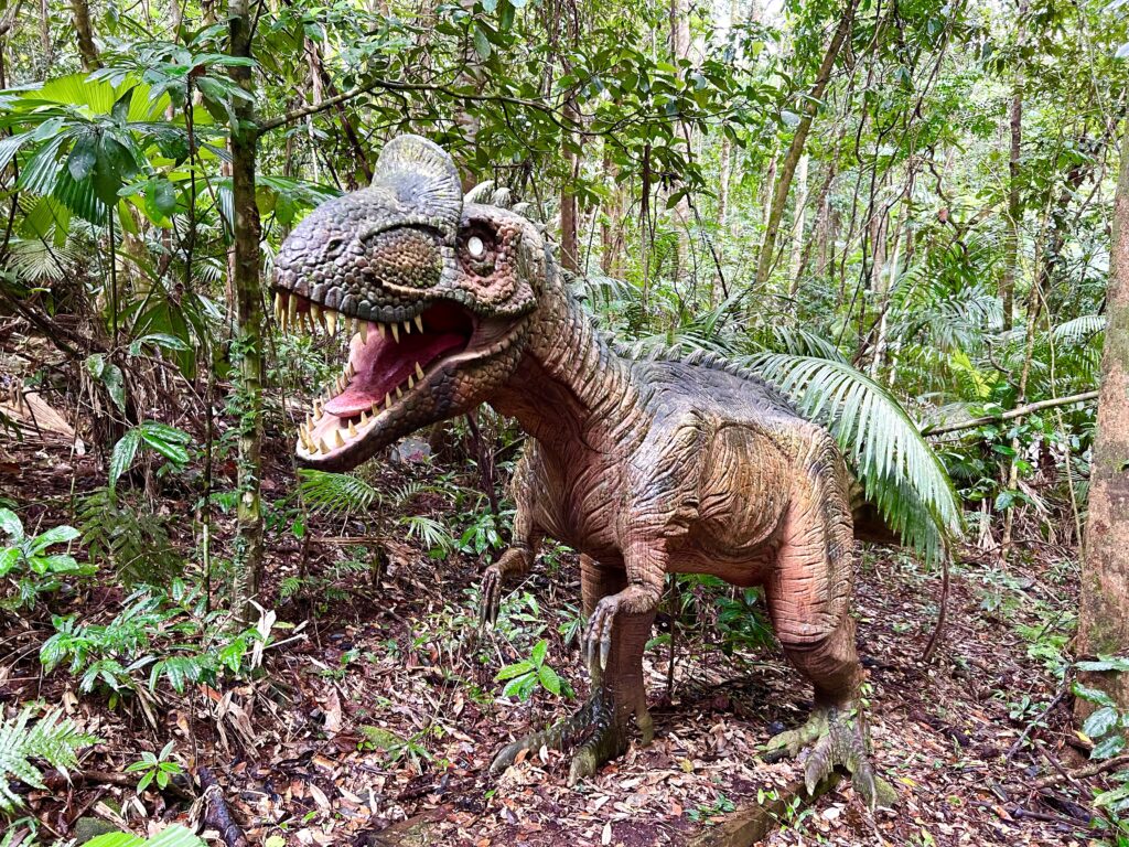 Fake dinosaur standing hidden in green rainforest.