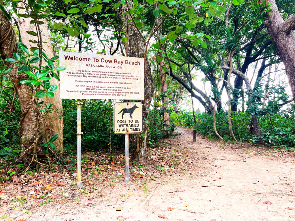 Welcome sign with warnings at entrance to Cow Bay Beach.