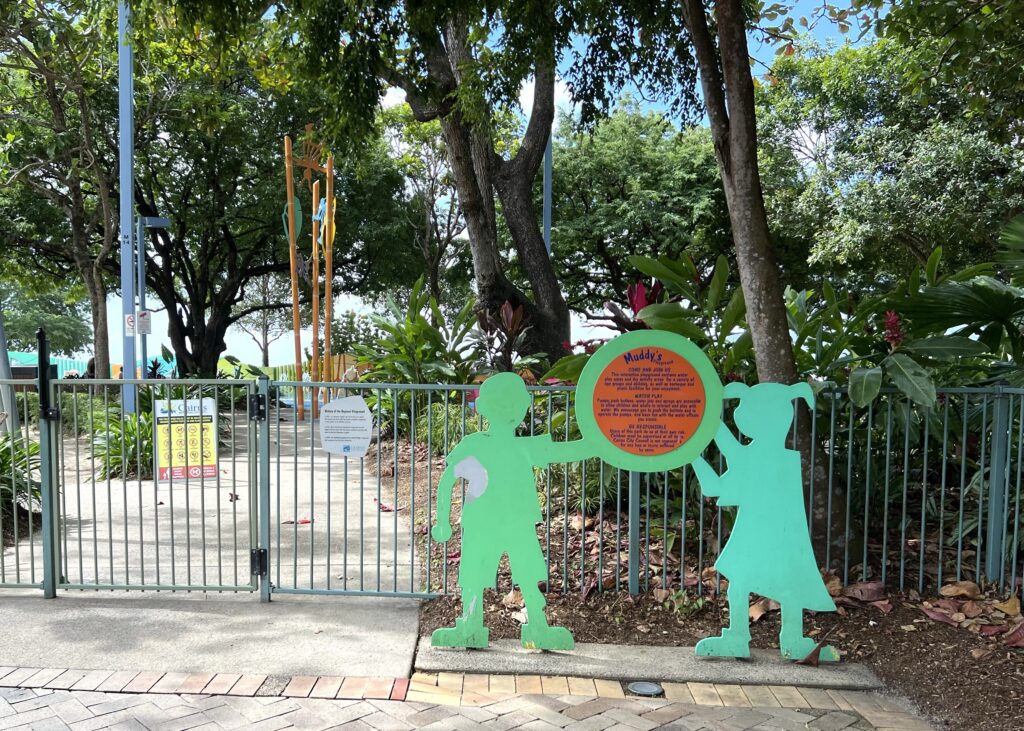 Entrance to playground with boy and girl cutouts displaying a sign with rules.