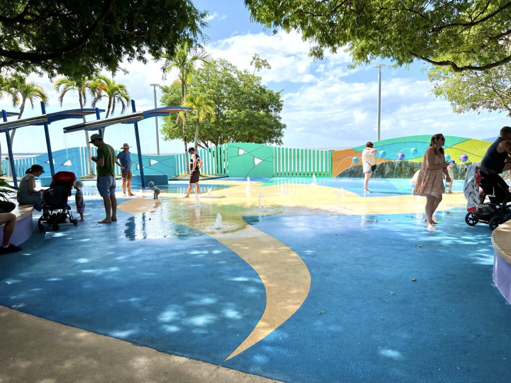 Adults and children enjoying an outdoor splash park.