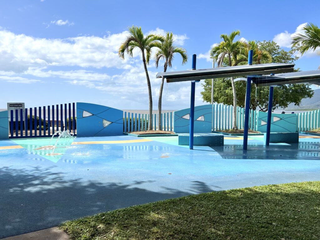 An empty outdoor splash park with palm trees in the background.