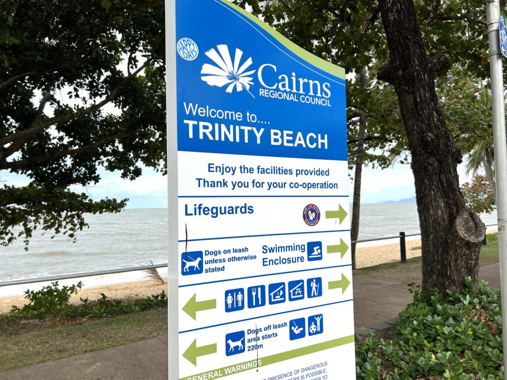 Sign next to beach with information about Trinity Beach, a suburb of Cairns you can visit during 5 days in Tropical North Queensland.