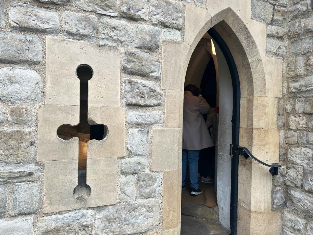A narrow carved window and an open doorway in a stone wall.