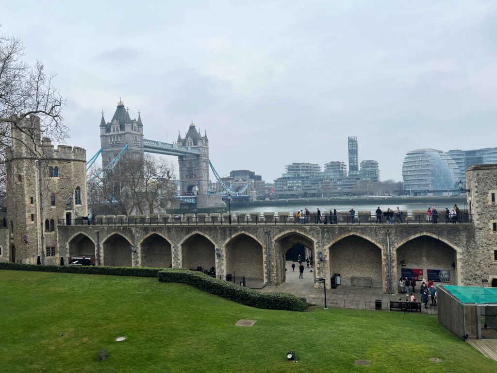 View across a green field towards Tower Bridge in London.