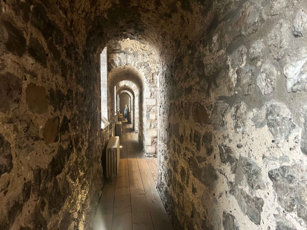 Looking down a long hallway with stone walls.