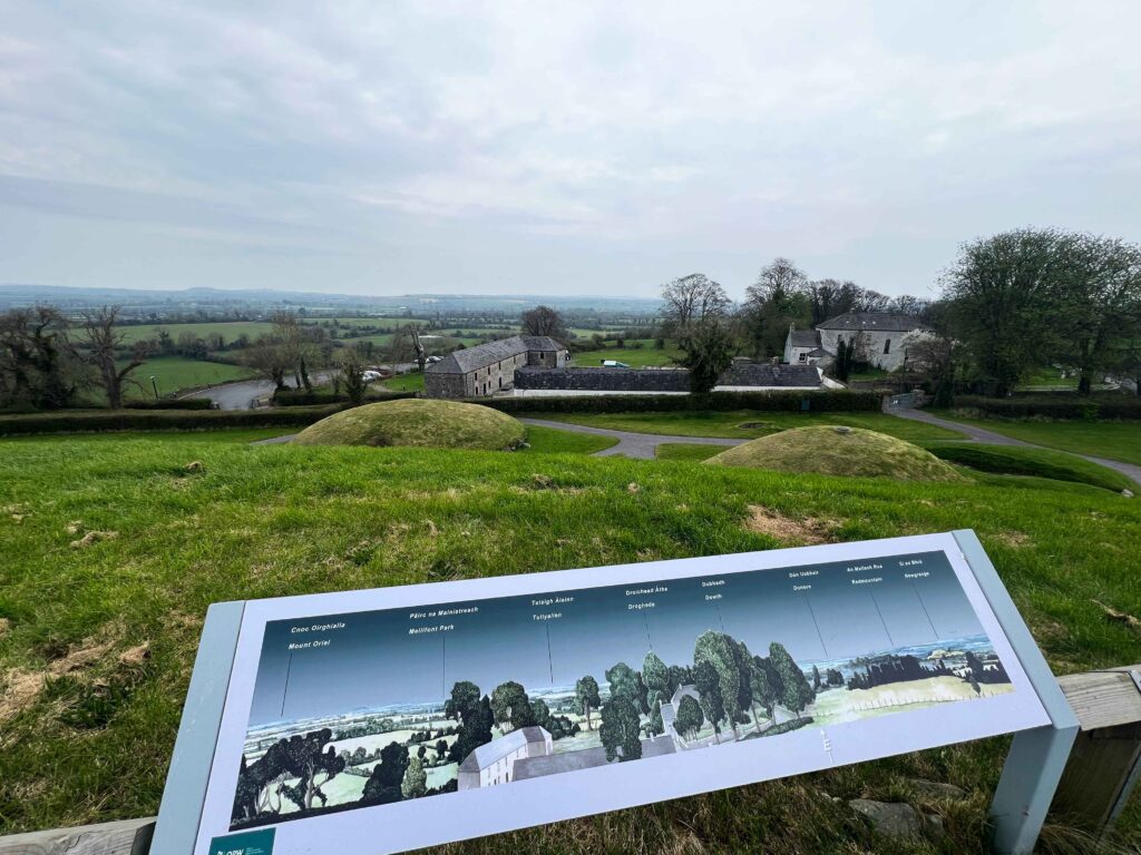 Placard sign looking over old buildings on green fields.