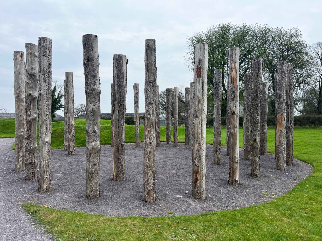 Wooden posts in ground in concentric circles.