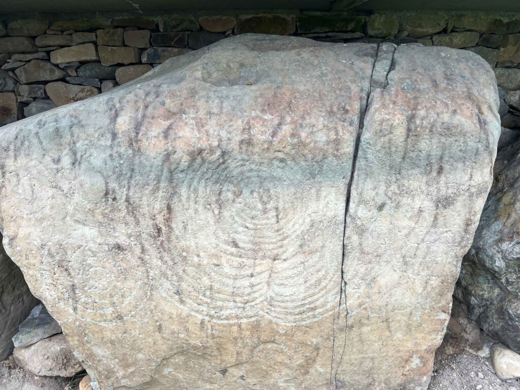Spiral carvings on a stone boulder.