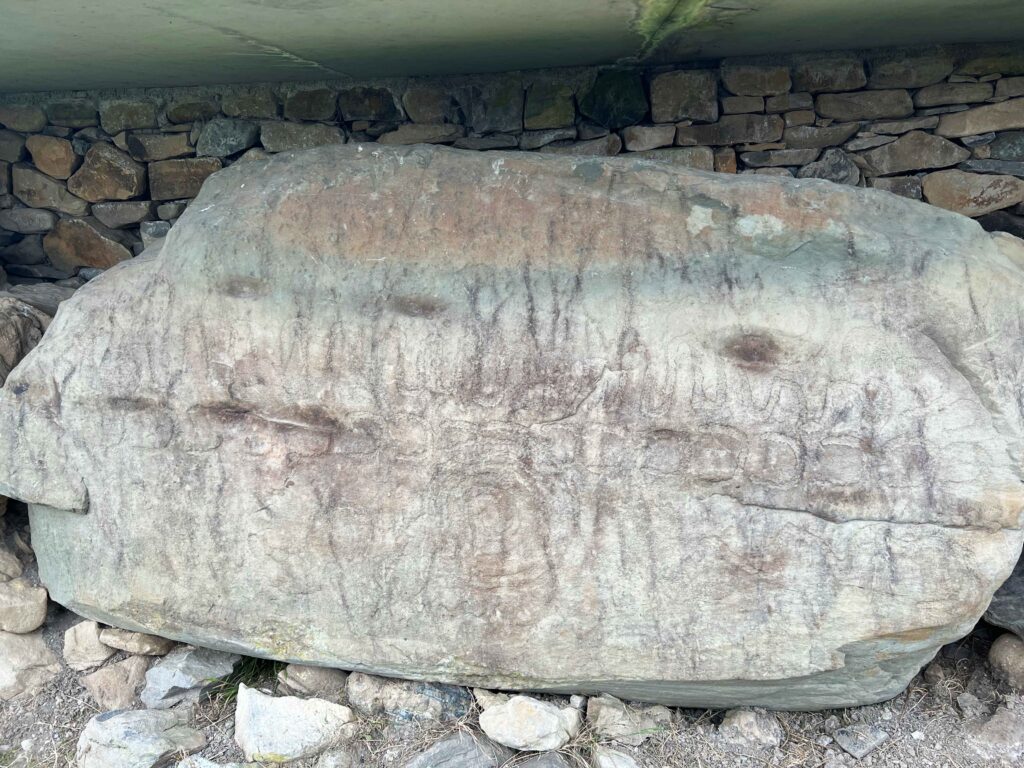 Crescent moon and wavy lines carved into a stone boulder, a must see on a stopover in Ireland.
