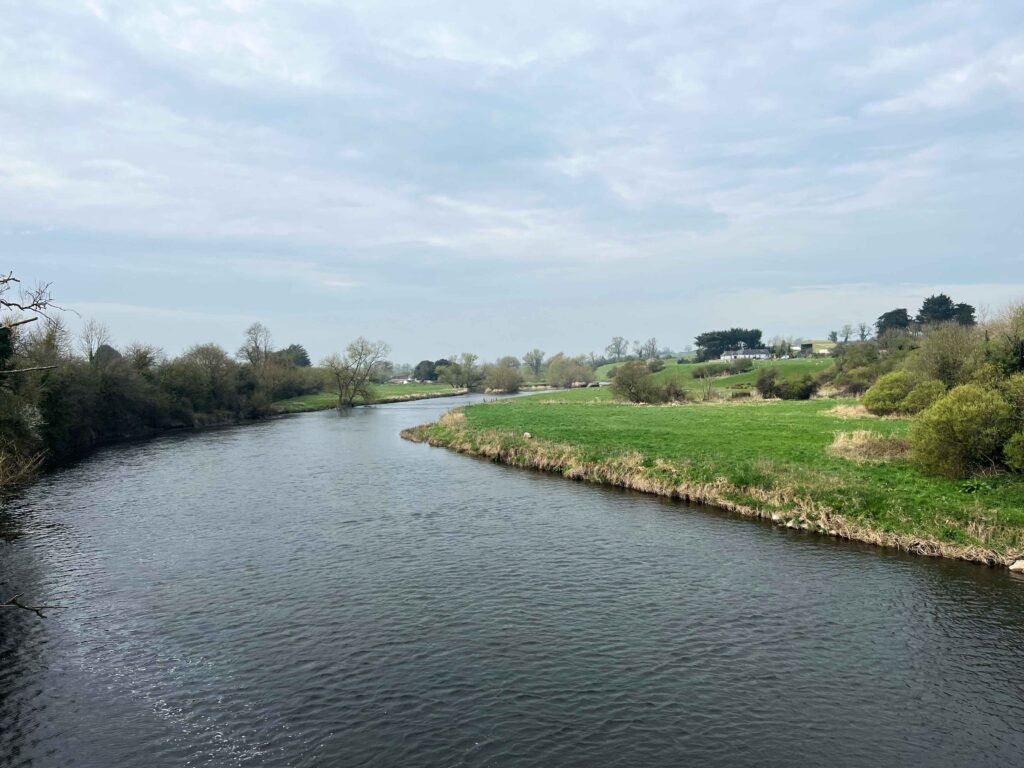 Narrow river next to green pasture in the country.