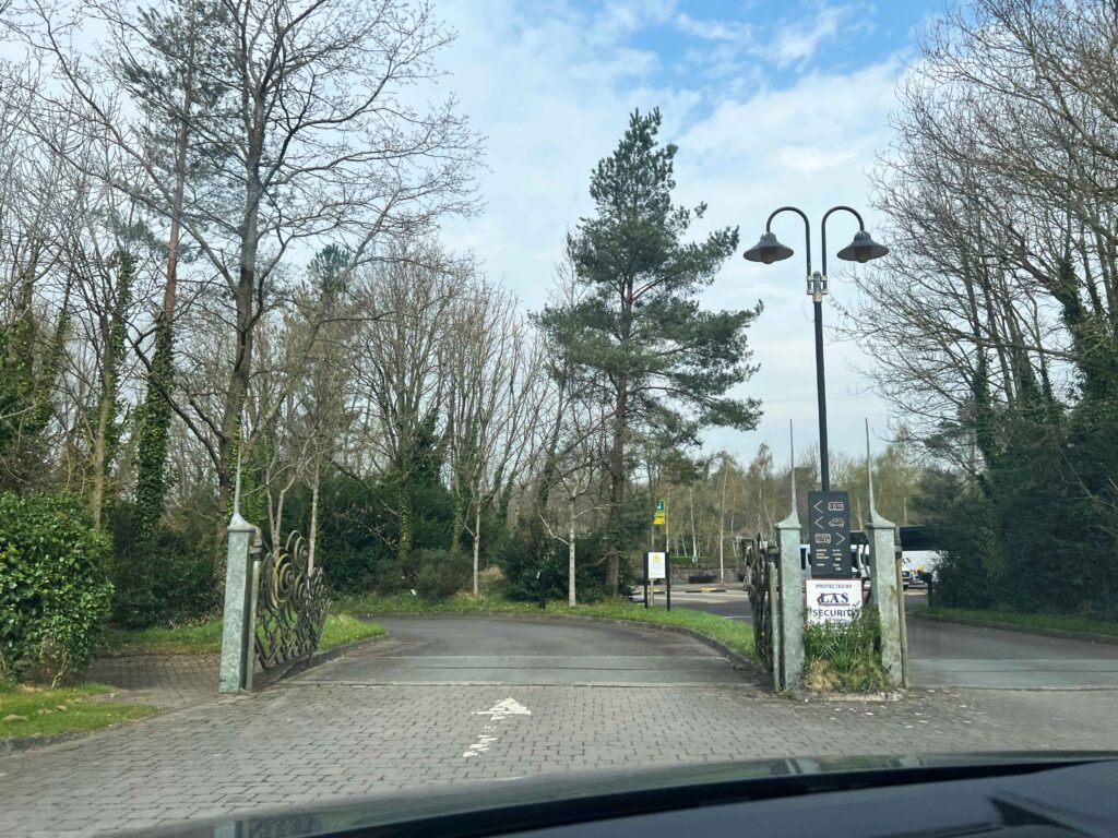 Entrance to a parking lot with lots of green trees.