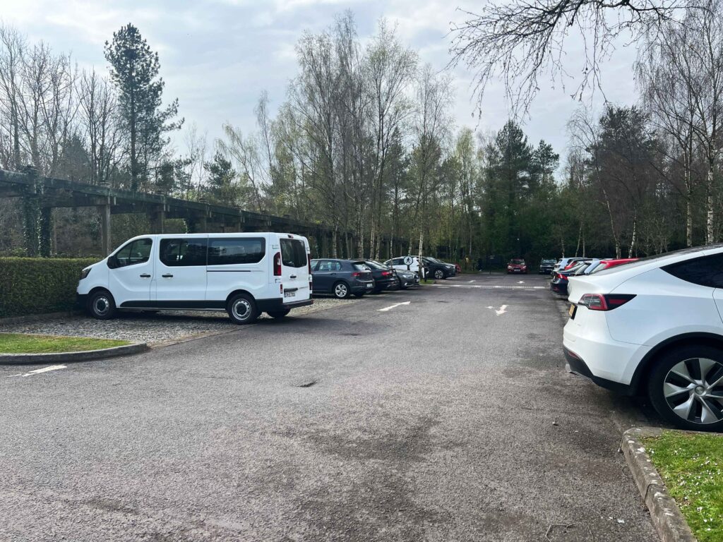 A parking lot with vehicles and lots of trees.