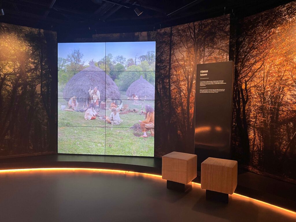 Large screen with image of people near huts.