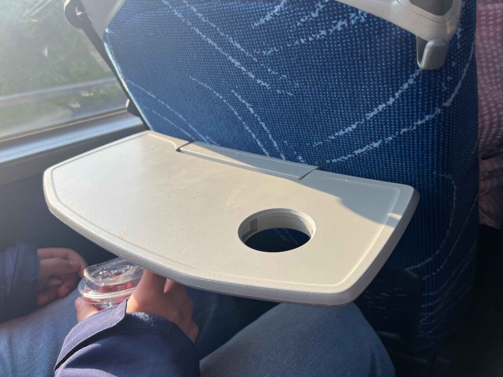 Table attached to back of a seat on a bus flipped down.