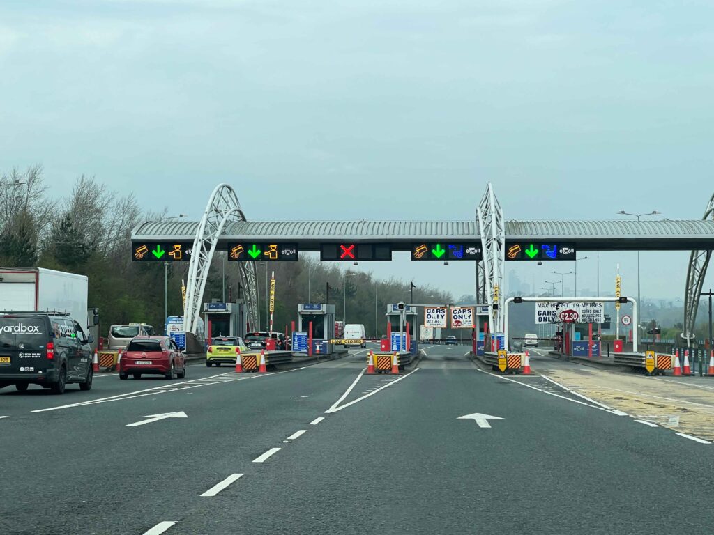 Cars waiting in line at a toll station on a highway.