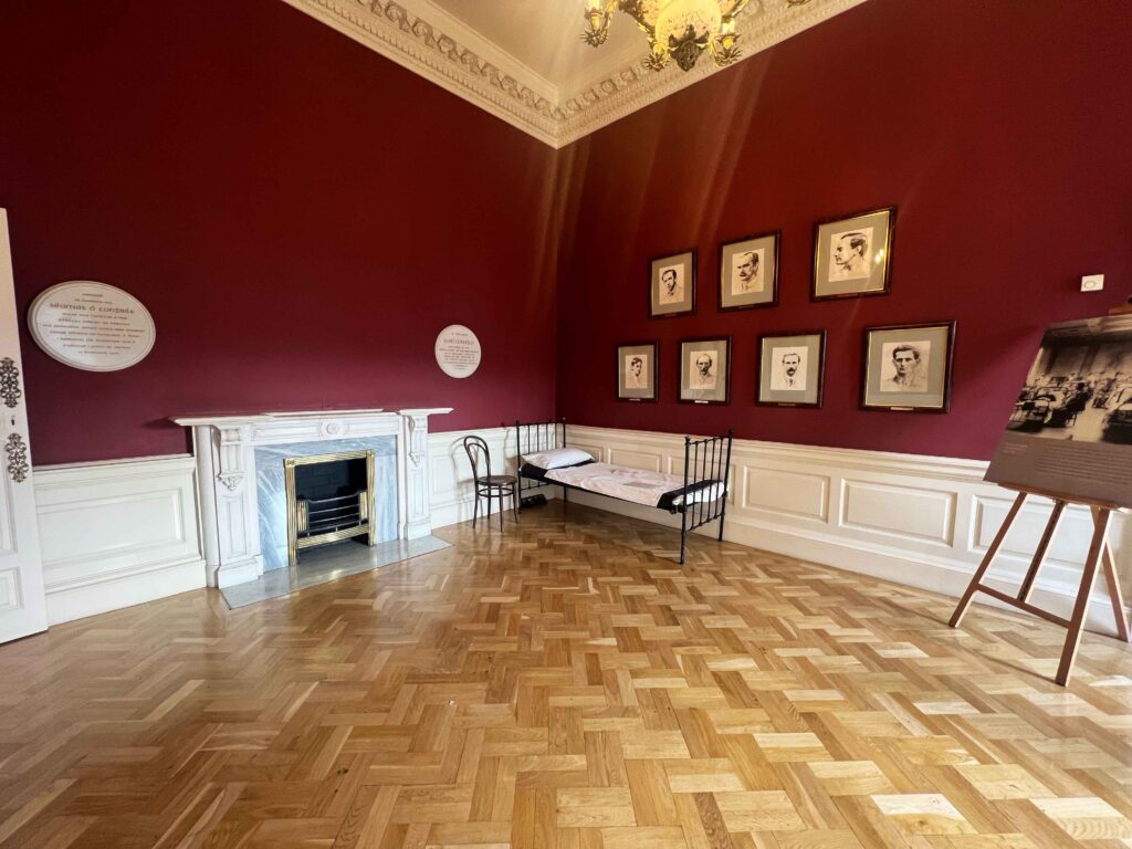 Old fireplace next to simple metal twin bed.