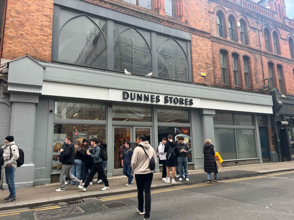 Exterior of a grocery store in a red brick building you may visit on a stopover in Ireland.