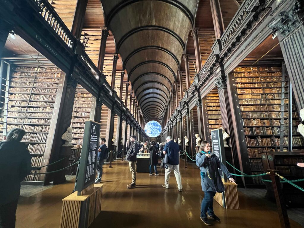 An illuminated digital earth suspended in air in a historic library.