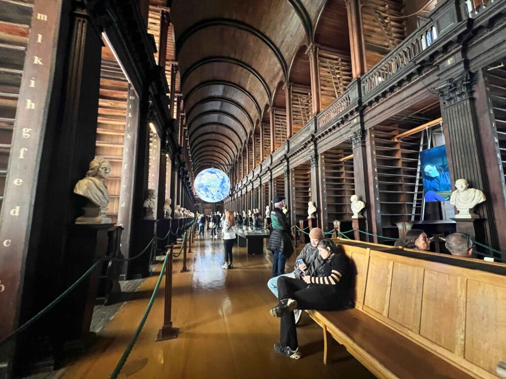 An illuminated digital earth suspended in air in a historic library.