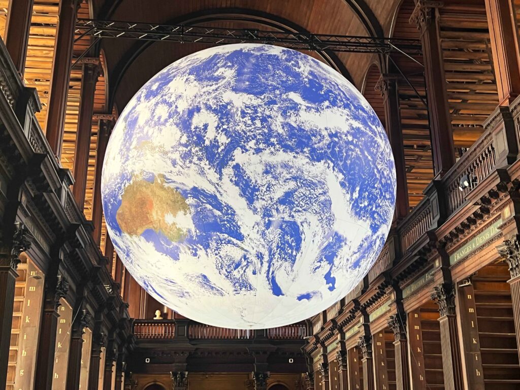 An illuminated digital earth suspended in air in a historic library, a must see on a stopover in Ireland.