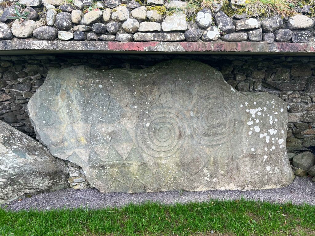 Spirals and diamonds carved on a boulder.