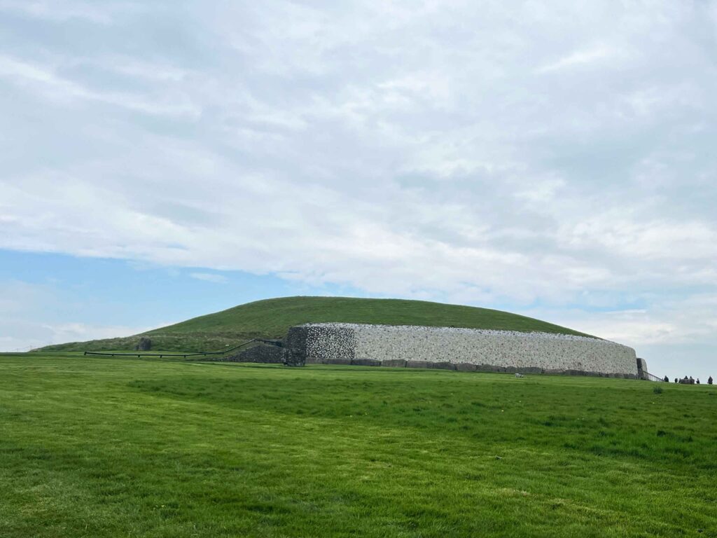Large green mound with stone wall around part of it.