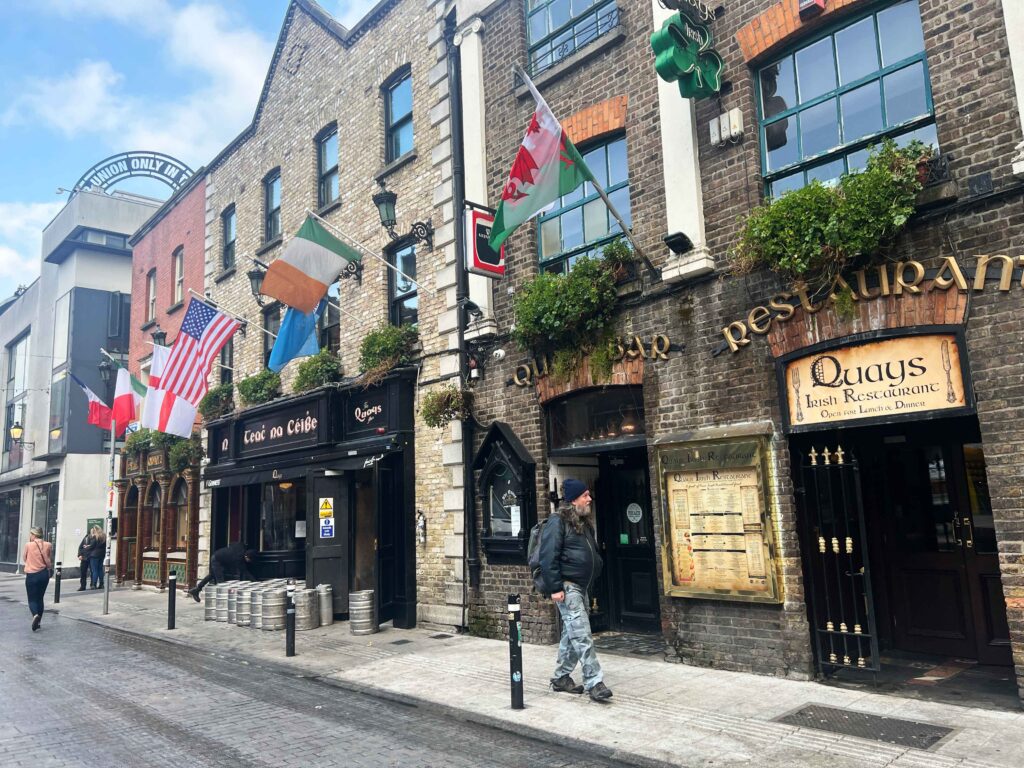 A cobbled street in Dublin with historic bulidings and many flags of different countries attached.